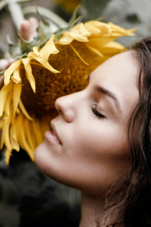 a woman holding a sunflower up to her face, profile image, ekaterina, with closed eyes, diffused natural skin glow