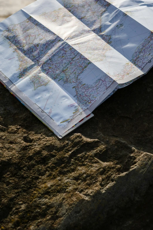 a blue and white towel sitting on top of a sandy beach, an album cover, by Jessie Algie, unsplash, regionalism, map cartography, rocky roads, slate, detail shot