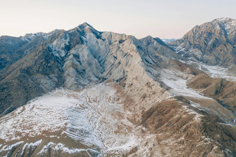 a man standing on top of a snow covered mountain, a detailed matte painting, by Simon Gaon, unsplash contest winner, sōsaku hanga, “ aerial view of a mountain, baotou china, erosion algorithm landscape, view from helicopter