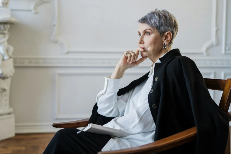 a woman sitting in a chair in a room, by Emma Andijewska, pexels, hyperrealism, short silver hair, elegant profile pose, androgynous person, sitting in dean's office