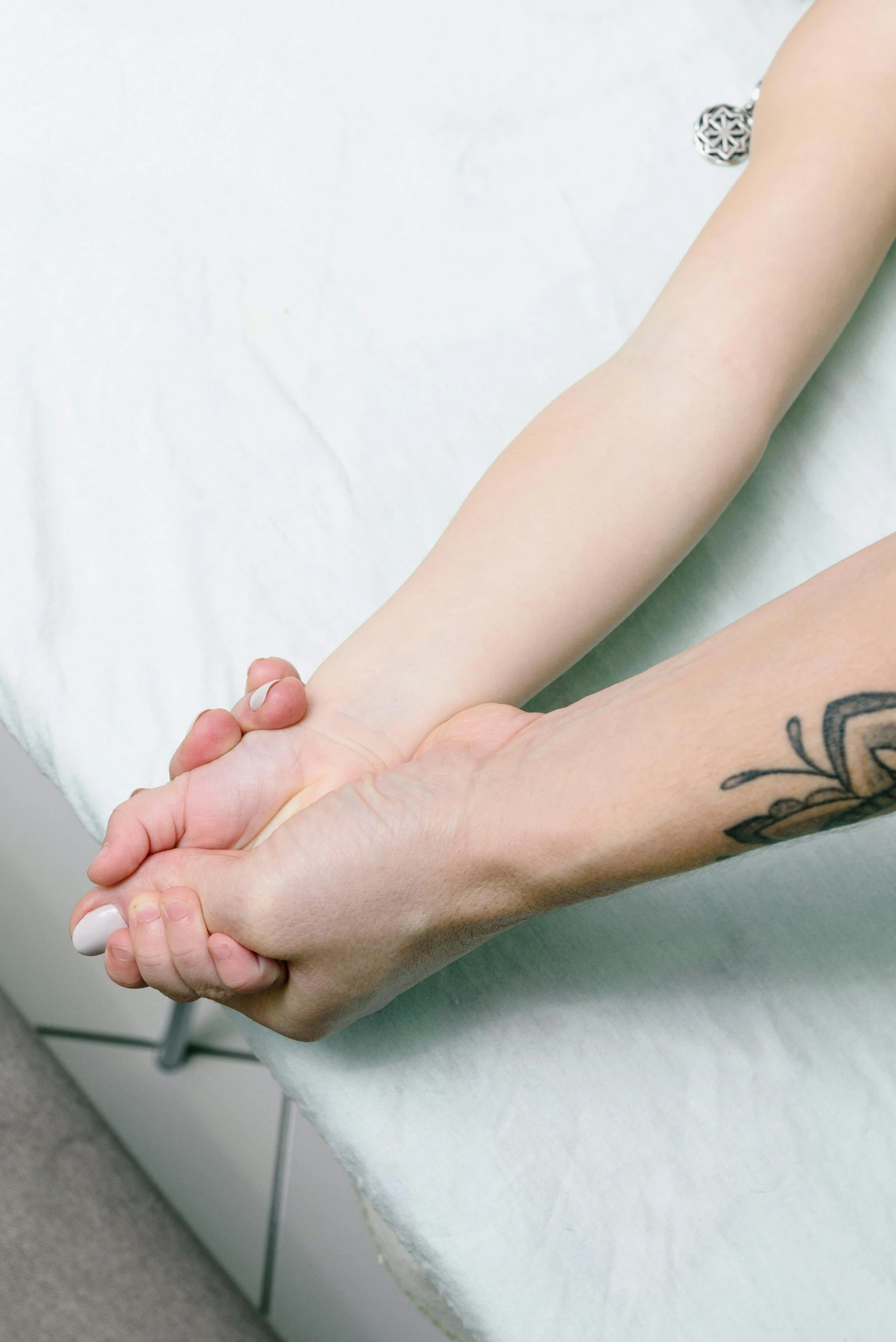 a woman sitting on a bed with a tattoo on her arm, a tattoo, by Victorine Foot, acupuncture treatment, holding each other hands, emily rajtkowski, panorama