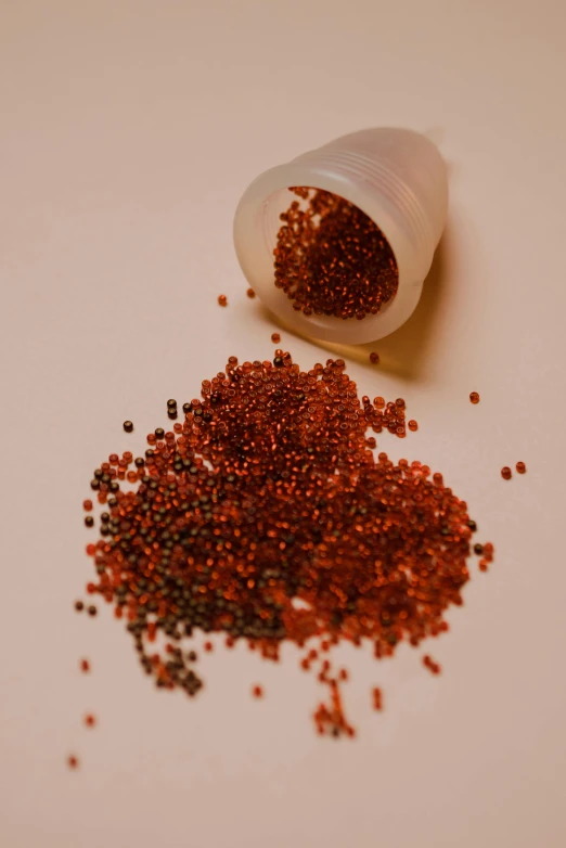 a pile of red sprinkles sitting on top of a table, by Attila Meszlenyi, pexels, pointillism, copper oxide material, miniature product photo, ( redhead, hibernation capsule close-up