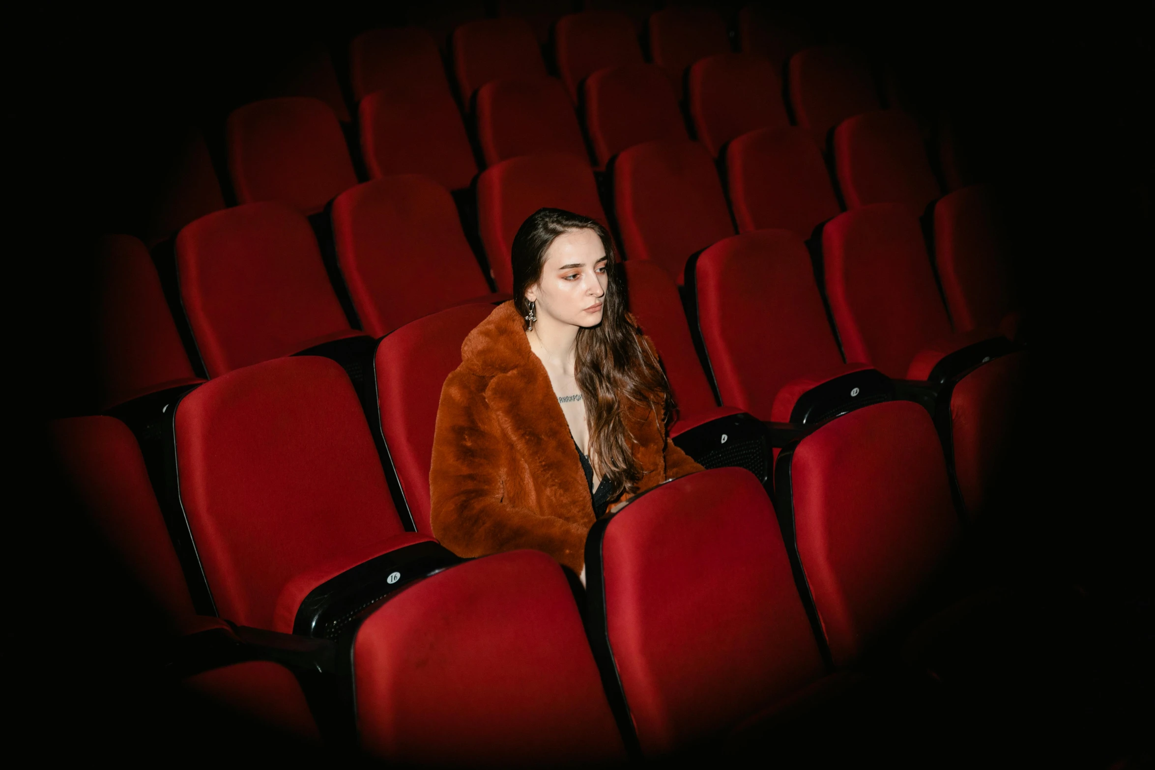 a woman in a fur coat sitting in a theater, pexels contest winner, antipodeans, dilraba dilmurat, monia merlo, rex orange county, red jacket