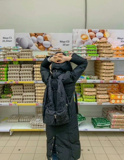 a woman standing in front of a display of eggs, by Emma Andijewska, stacking supermarket shelves, billie eilish, very accurate photo, tourist photo