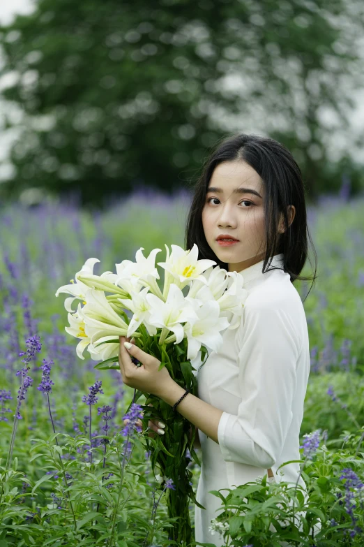 a woman holding a bunch of flowers in a field, inspired by Yi Yuanji, unsplash, white lilies, dilraba dilmurat, portait image, lush surroundings