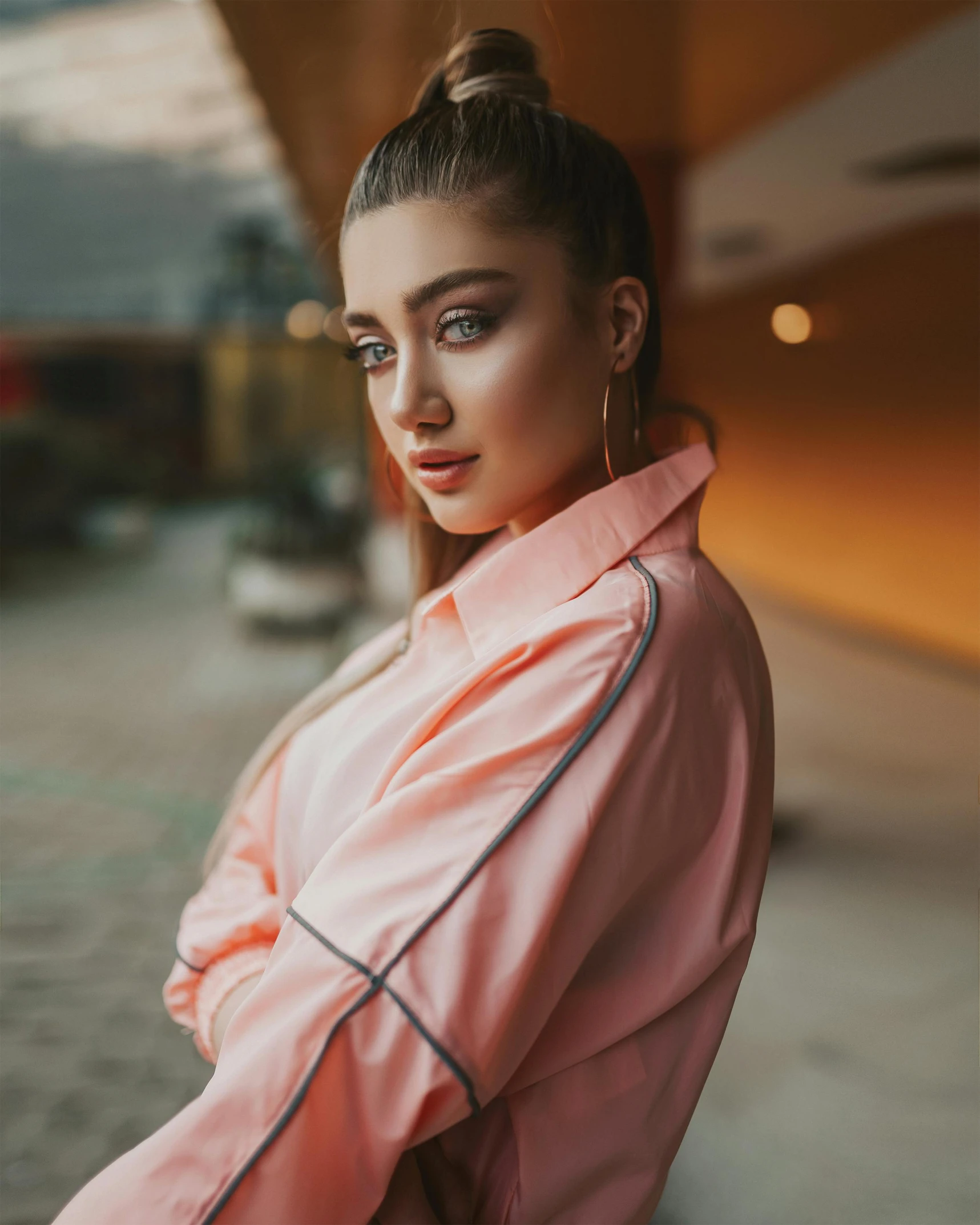 a woman in a pink jacket leaning against a wall, inspired by Elsa Bleda, trending on pexels, renaissance, portrait of ariana grande, wearing an orange t shirt, attractive androgynous humanoid, wearing a track suit