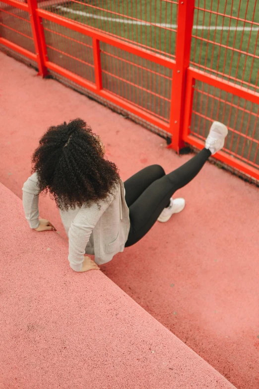 a woman sitting on the ground in front of a fence, pexels contest winner, happening, people falling off a playground, leggings, back arched, ashteroth