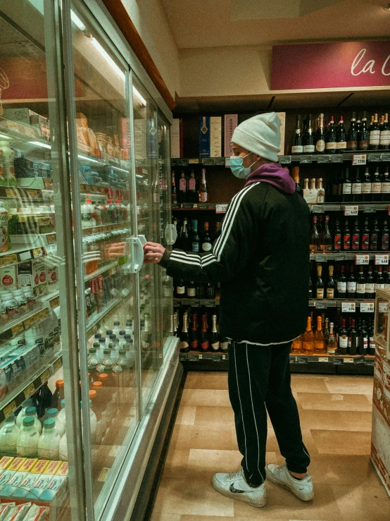 a person standing in front of a refrigerator in a store, by Thomas Furlong, pexels, fortninte, cellar, thumbnail, winter