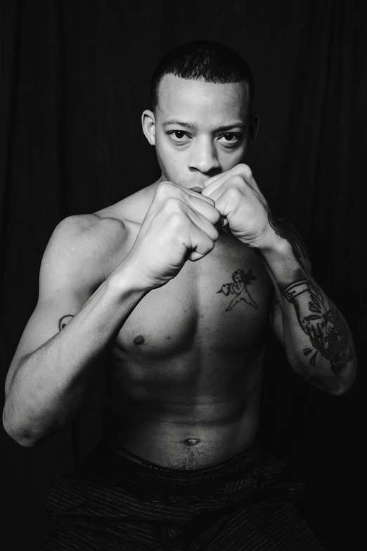 a black and white photo of a man with tattoos, an album cover, inspired by Felix-Kelly, hyperrealism, boxing stance, gustavo fring, black teenage boy, pete davidson