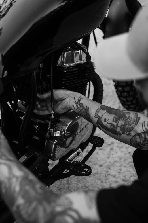 a black and white photo of a man working on a motorcycle, a tattoo, by Davide Sasselli, uploaded, hands, morning detail, mac miller