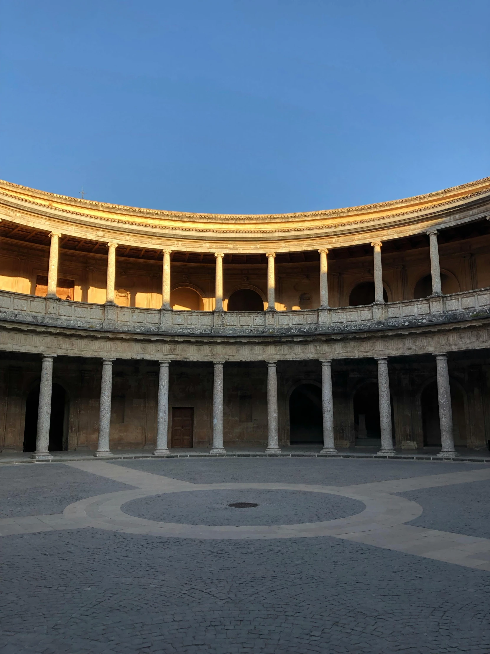 a circular building with columns and a sky background, inspired by Luis Paret y Alcazar, unsplash, renaissance, a wide open courtyard in an epic, square, golden glow, diego velazquez