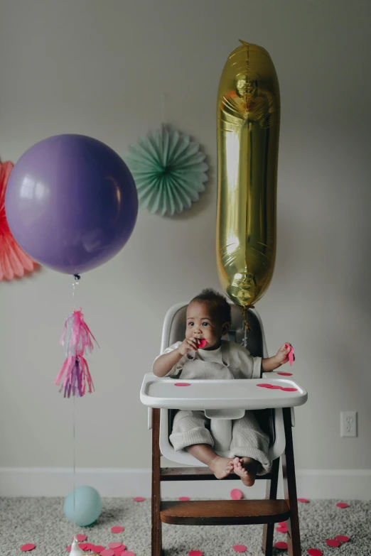 a baby sitting in a high chair in front of balloons, a portrait, pexels, dwell, parties, violet myers, a still of a happy