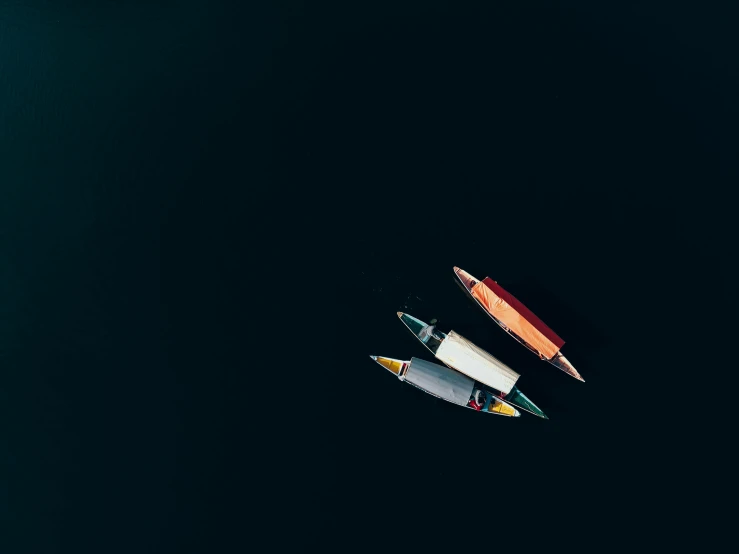 a couple of boats floating on top of a body of water, by Sebastian Spreng, unsplash contest winner, minimalism, three colors, against a deep black background, looking down on the camera, small canoes