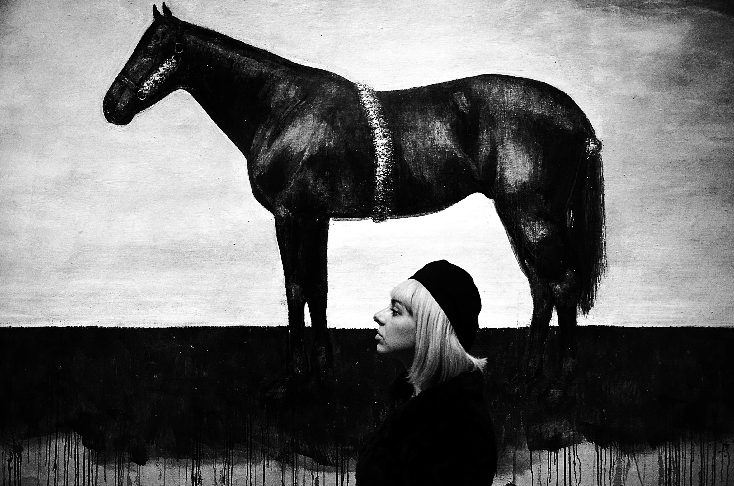 a woman standing in front of a painting of a horse, a charcoal drawing, by Lucia Peka, tumblr, surrealism, trending on saatchi art, frank moth, elisabeth moss, kerli koiv