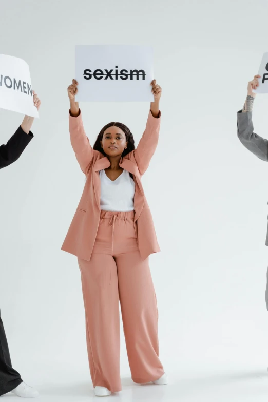 a group of people holding signs that say sexism, by Arabella Rankin, trending on pexels, 3 - piece, on a pale background, wearing a suits, an artistic pose