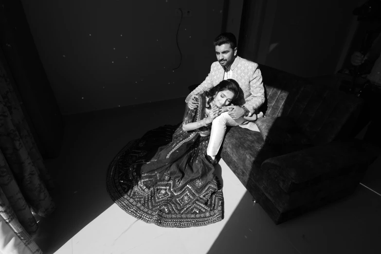 a man sitting on top of a couch next to a woman, a black and white photo, unsplash, haute couture fashion shoot, portrait image, wedding photo, lying down