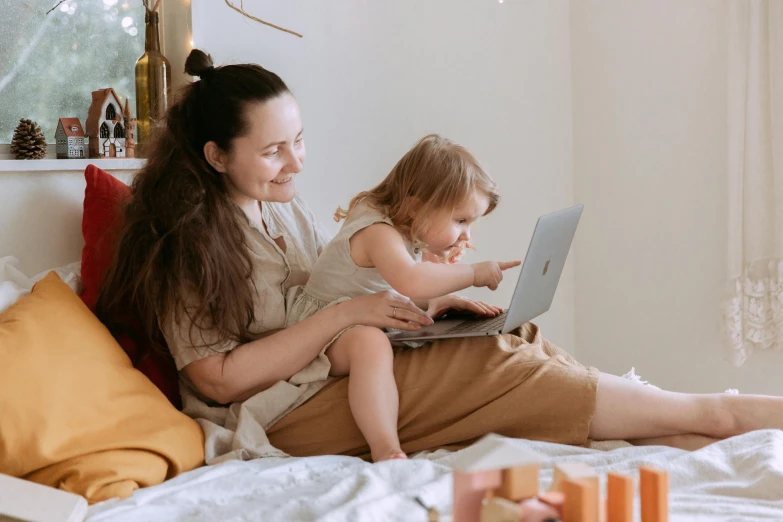 a woman and child sitting on a bed with a laptop, pexels contest winner, avatar image, casual playrix games, brown, people at work