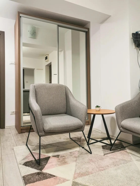 a living room with two chairs and a table, by Adam Marczyński, grey, in a comfortable chair, neo kyiv, furnished room