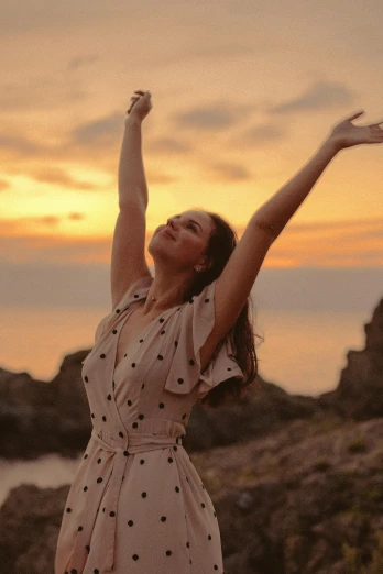 a woman standing on top of a hill next to the ocean, pexels contest winner, happening, graceful arms, she expressing joy, photo of the beauty gal gadot, warm glow