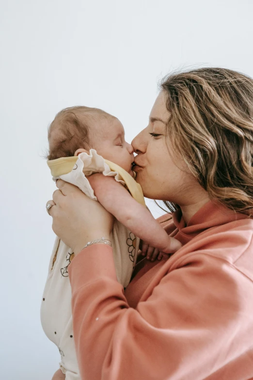 a woman holding a baby in her arms, pexels contest winner, kissing together, charli bowater and artgeem, profile image, clean design