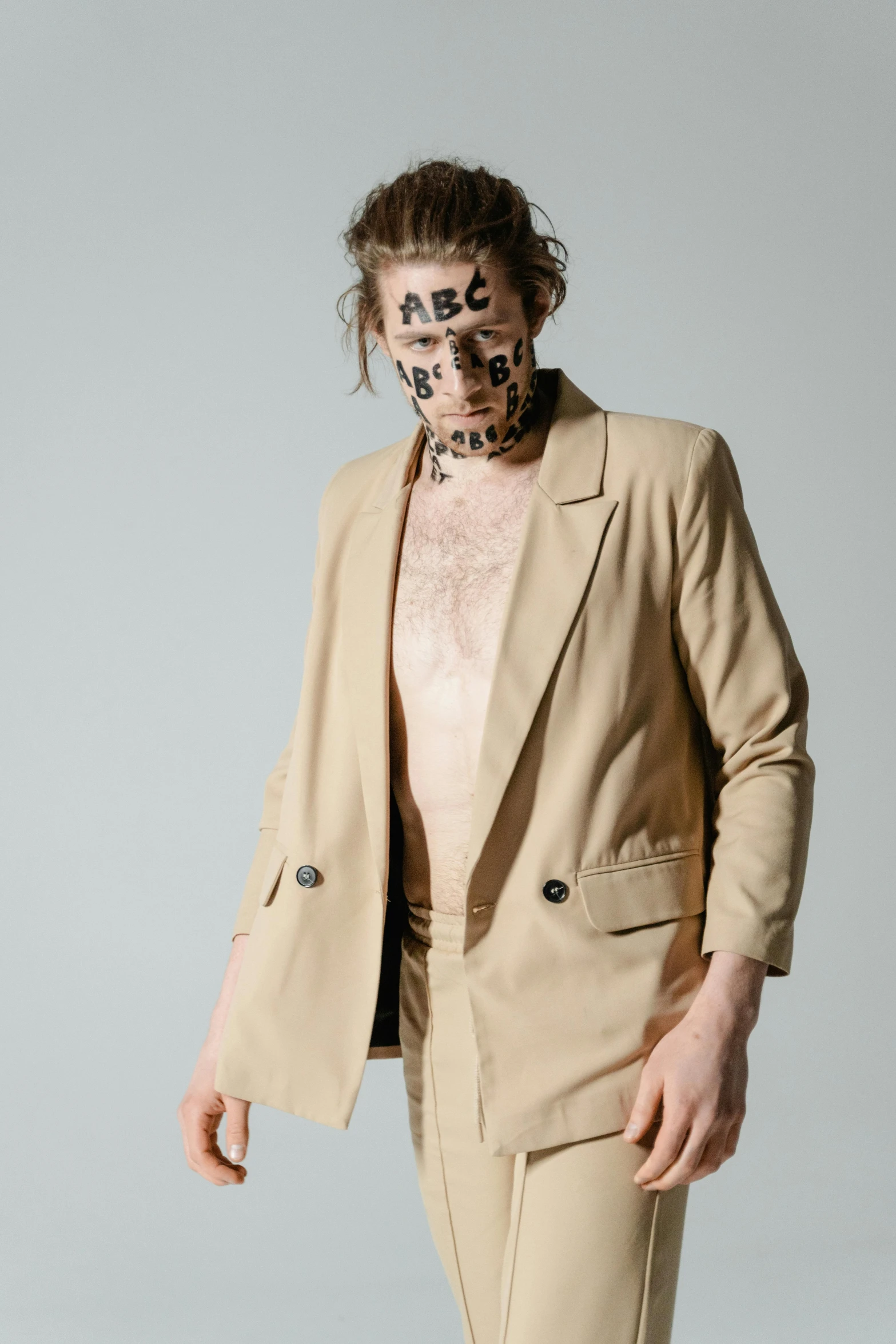 a man in a tan suit with a leopard print on his face, by Nina Hamnett, kaki body suit, xqc, wearing bandit mask, non binary model