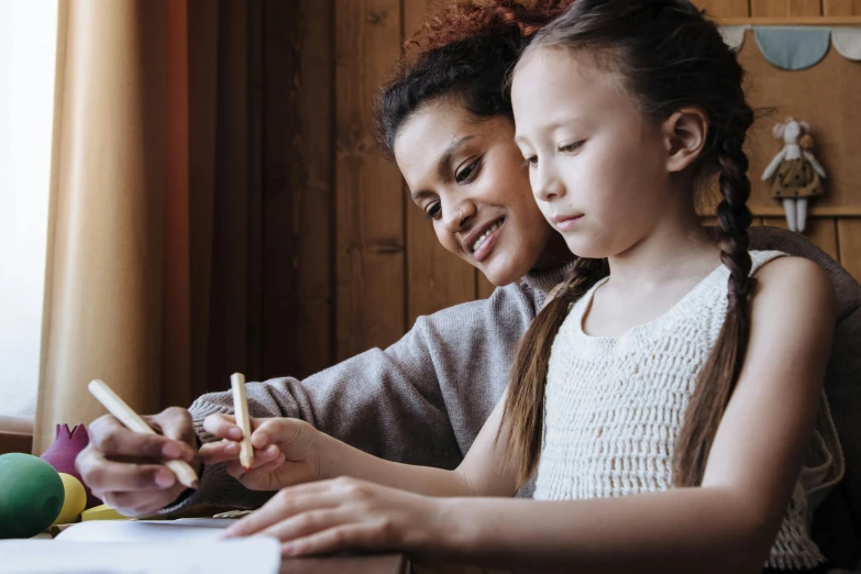 a woman and a little girl sitting at a table, a child's drawing, by Lee Loughridge, pexels contest winner, arts and crafts movement, brown, holding pencil, varying ethnicities, thumbnail