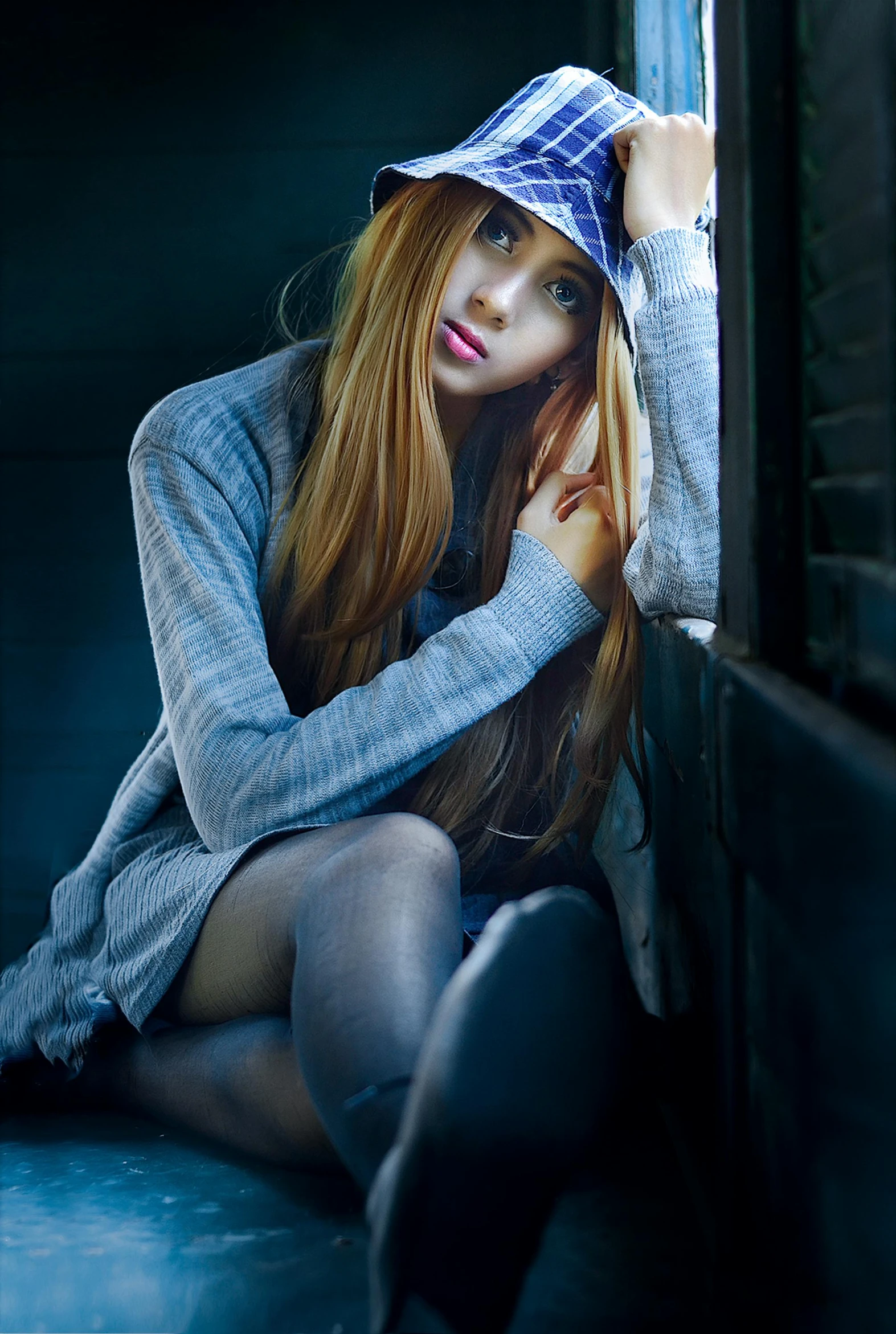 a woman sitting on the floor next to a window, a portrait, unsplash, asuka langley souryuu, wearing beanie, moody blue lighting, sat down in train aile