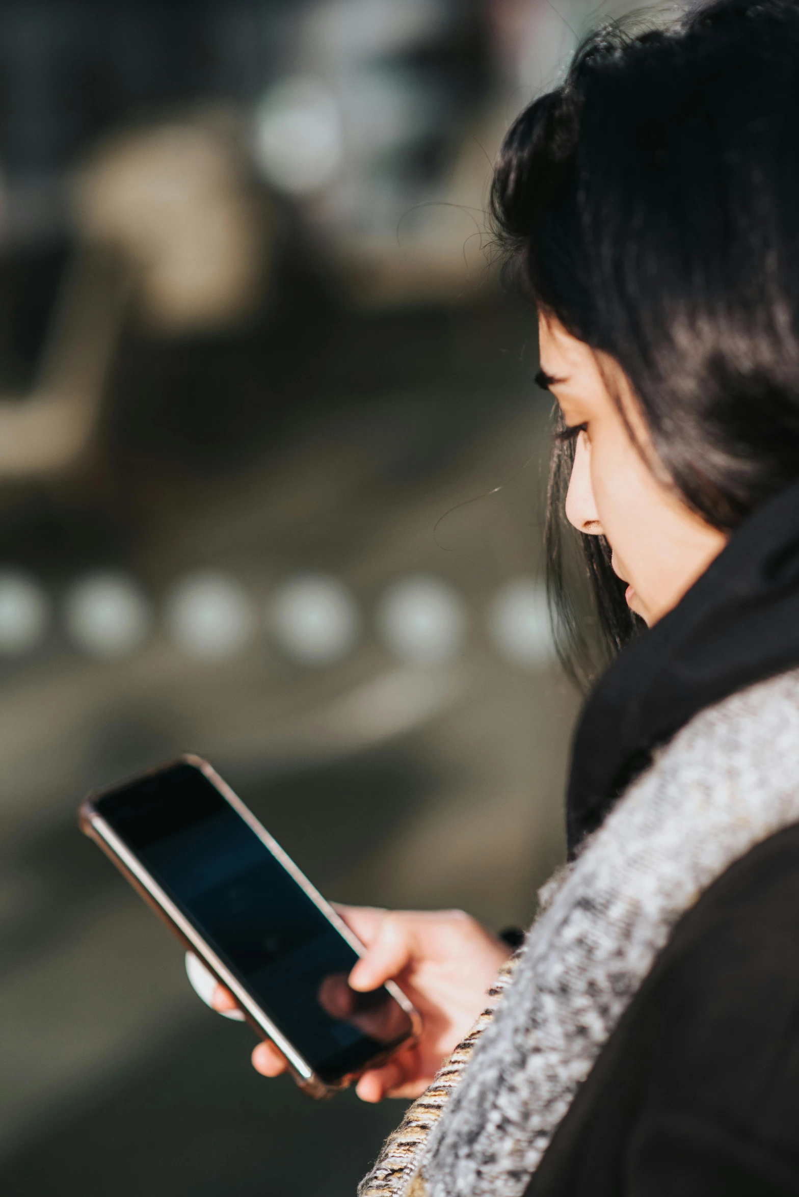 a woman is looking at her cell phone, trending on pexels, woman with black hair, slightly pixelated, outside, digital image