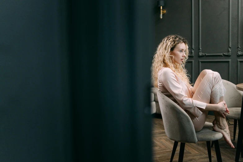 a woman sitting on a chair in a room, curly blonde hair | d & d, portrait featured on unsplash, panoramic view of girl, high quality image