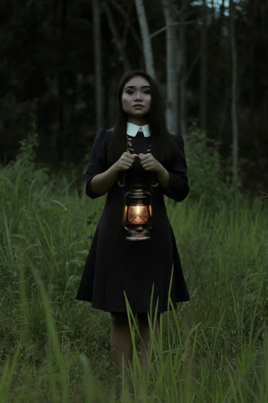 a woman standing in a field holding a lantern, inspired by Brooke Shaden, unsplash, conceptual art, as wednesday addams, still from a live action movie, profile pic, dark woods in the background