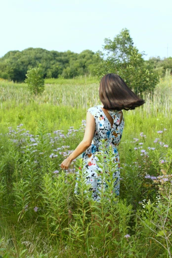 a woman standing in a field of tall grass, by Pamela Drew, unsplash, conceptual art, flowery dress, filled with plants and habitats, prairie in background, minn