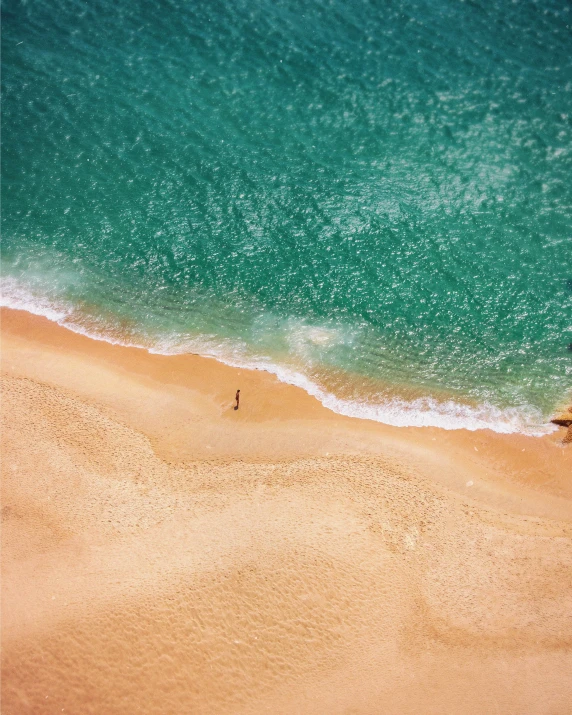 a couple of umbrellas sitting on top of a sandy beach, pexels contest winner, minimalism, helicopter view, swimming in ocean, gif, golden hues