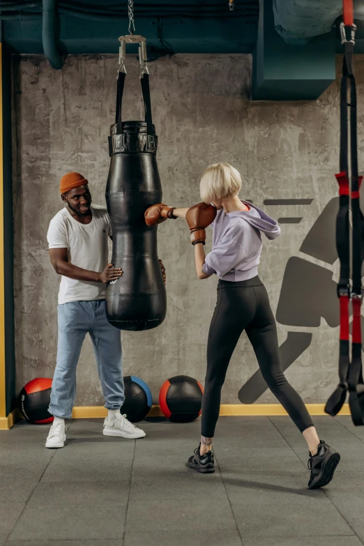 a woman hitting a punching bag in a gym, poster art, pexels contest winner, man and woman, jemal shabazz, full-body, 15081959 21121991 01012000 4k