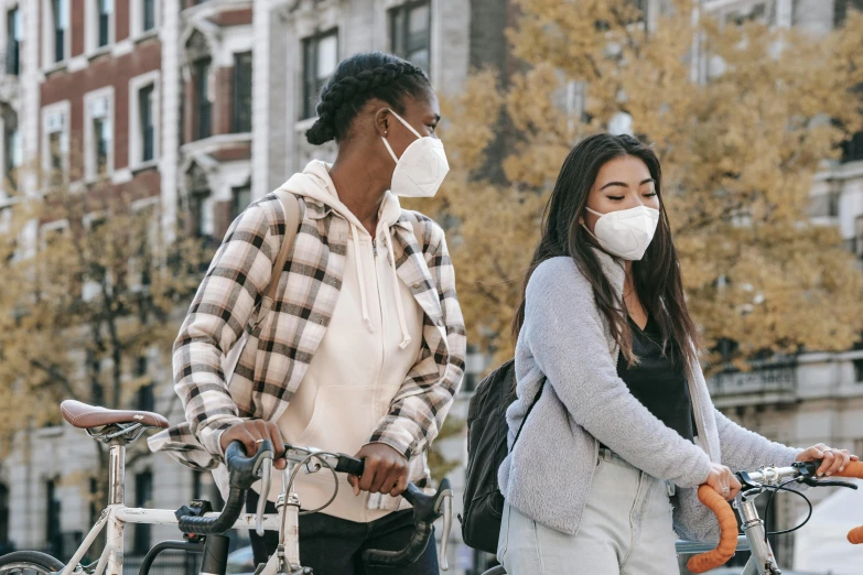 a man and a woman on bicycles wearing face masks, by Emma Andijewska, trending on pexels, two girls, standing in township street, sustainable materials, woman holding another woman
