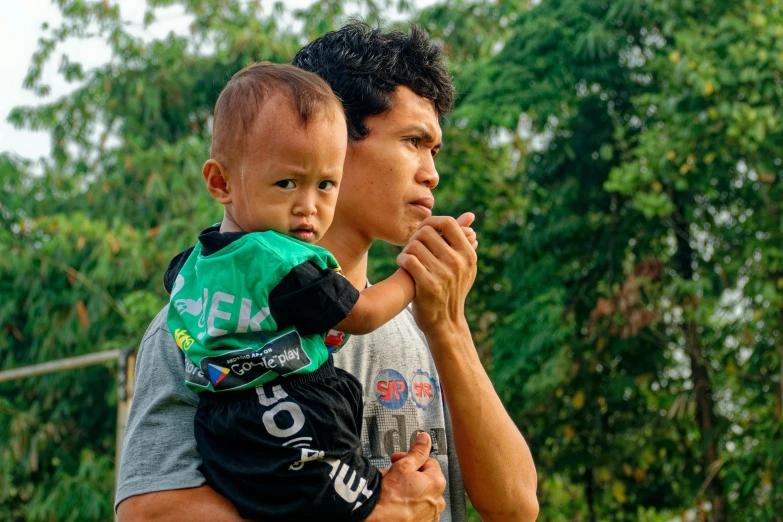 a man holding a small child in his arms, pexels contest winner, sumatraism, avatar image, thumbnail, looking serious, cambodia