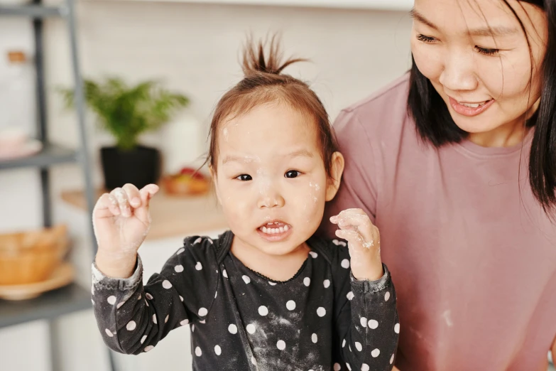 a woman putting icing on a child's face, inspired by Yukimasa Ida, pexels contest winner, mingei, pigtails hair, manuka, thumbnail, portrait of tall