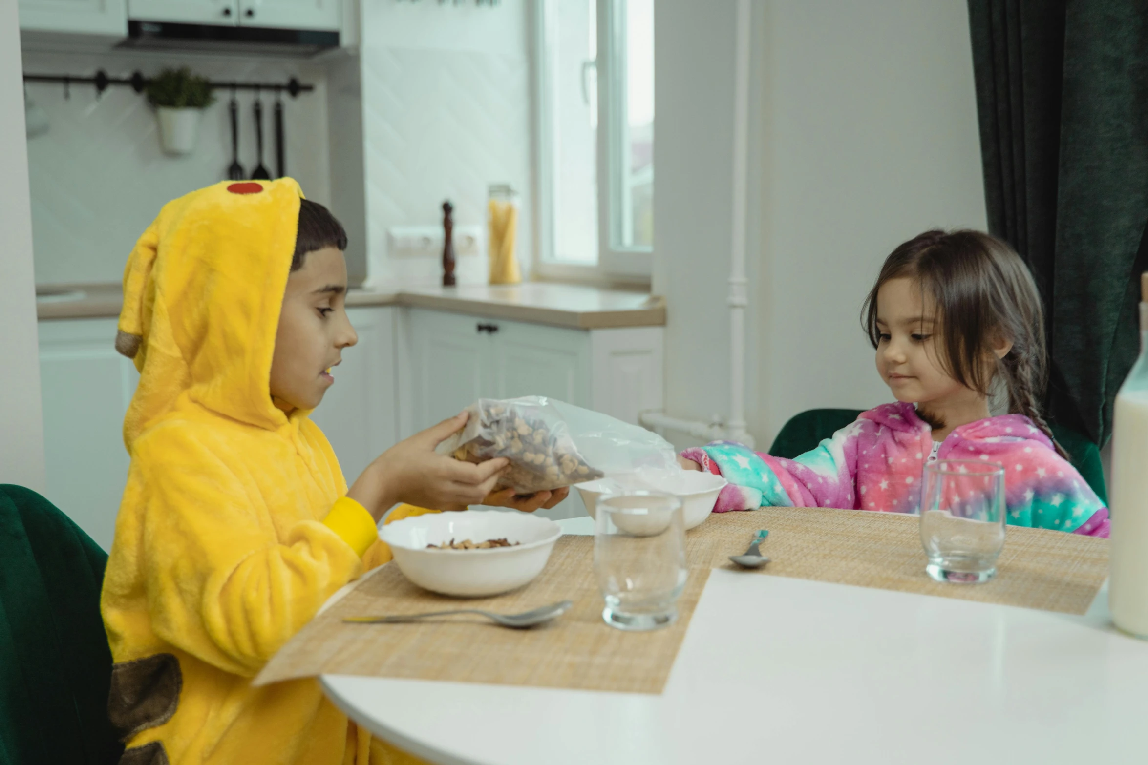 a couple of kids that are sitting at a table, pexels contest winner, wearing a yellow hoodie, cereal box, wearing pajamas, people inside eating meals