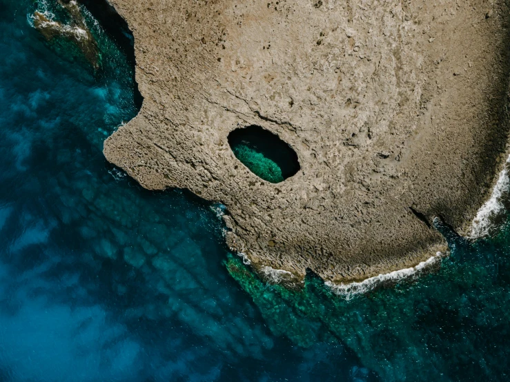 a large body of water next to a sandy beach, by Simon Marmion, pexels contest winner, hurufiyya, marble hole, aerial, grotto, floating. greenish blue