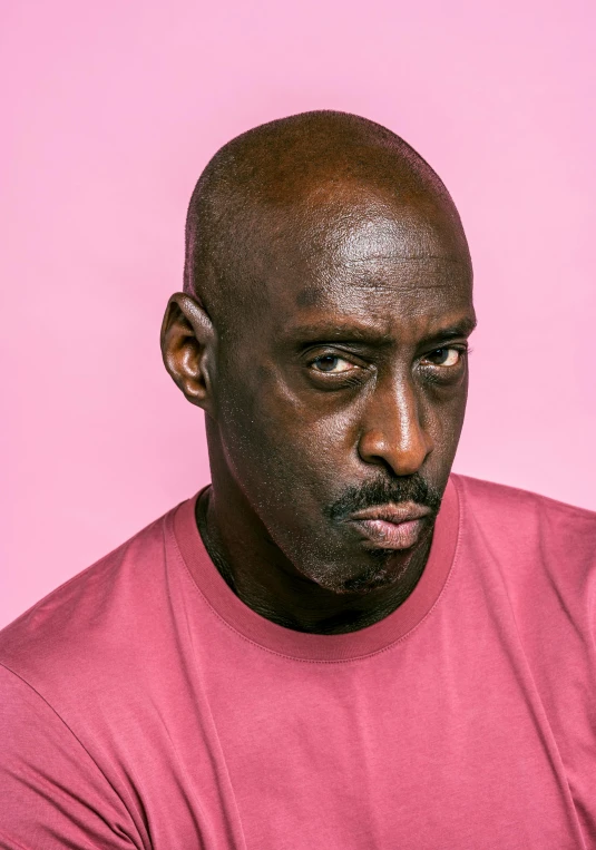 a man in a pink shirt holding a cell phone, lance reddick, plain background, instagram post, jean deville