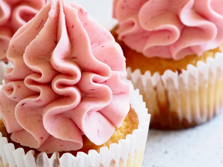 a close up of three cupcakes with pink frosting, by Eleanor Best, trending on pexels, intricate pasta waves, raspberry, manuka, thumbnail