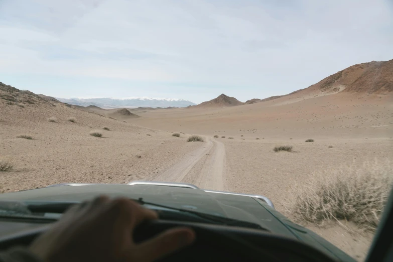 a person driving a vehicle on a dirt road, by Daren Bader, les nabis, ancient mongolian elon musk, ground level camera view, background image, andes