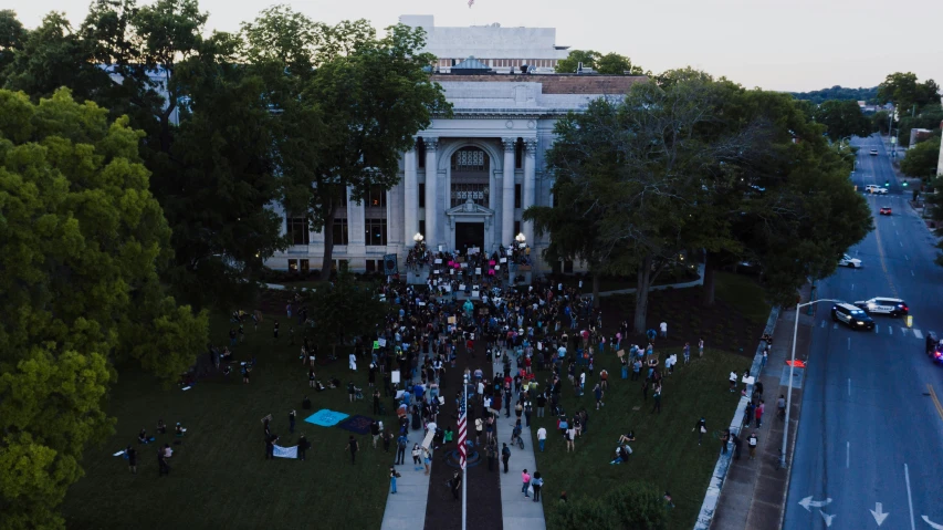 a large group of people standing in front of a building, by Ryan Pancoast, arial shot, official courthouse, late summer evening, protest