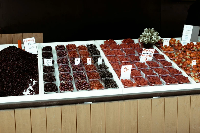 a table topped with lots of different types of fruit, a colorized photo, by Attila Meszlenyi, maroon red, shops, seeds, 35 mm photo