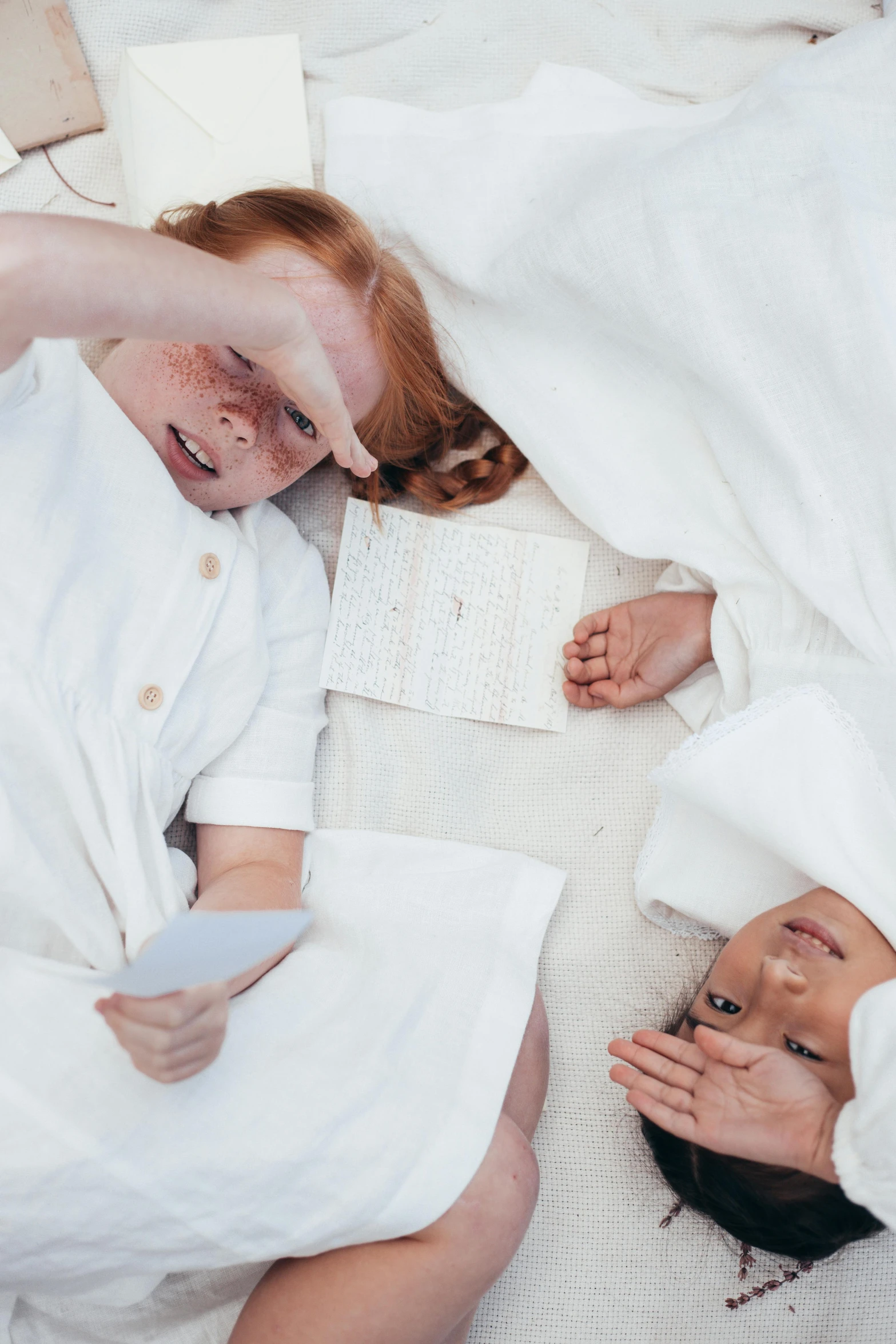 a couple of people laying on top of a bed, an album cover, by Ruth Simpson, pexels contest winner, brunette boy and redhead boy, dressed in white robes, scientific photo, white freckles