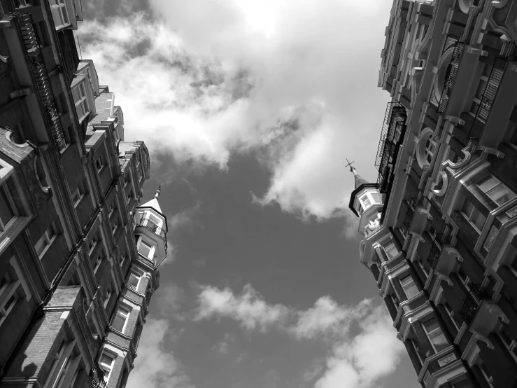 a black and white photo of a clock tower, a black and white photo, inspired by Thomas Struth, unsplash, precisionism, view of houses in amsterdam, two towers, wide angel shot from below, summer 2016