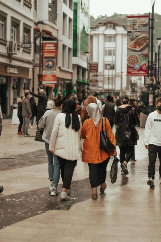 a group of people walking down a street, hijab, malls, wales, covid-19 as a human