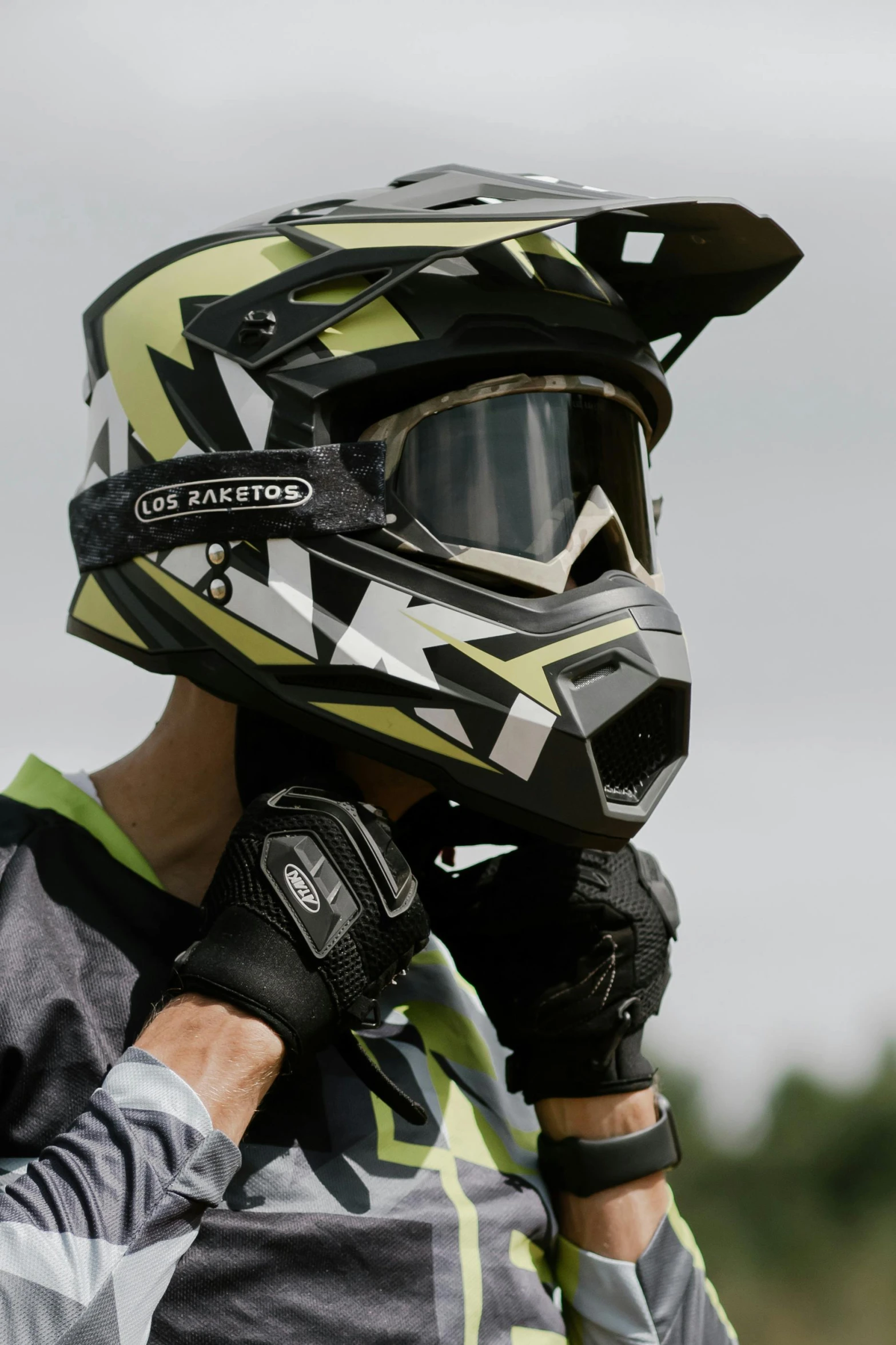 a man wearing a helmet talking on a cell phone, mx2, green facemask, detailed shot, black and yellow scheme