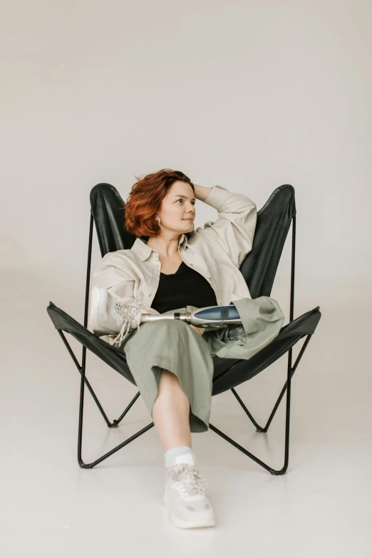 a woman sitting in a chair reading a book, a portrait, pexels contest winner, ( redhead, woman in streetwear, full body potrait holding bottle, sitting on top of a cryopod