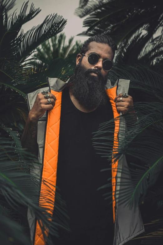 a man with a beard wearing an orange vest, an album cover, unsplash, tall plants, dark shades, outlive streetwear collection, metal garments