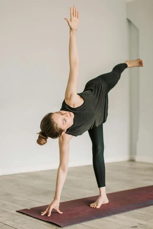 a woman doing a yoga pose on a yoga mat, unsplash, arabesque, ouchh and and innate studio, manuka, standing sideways, sam shearon